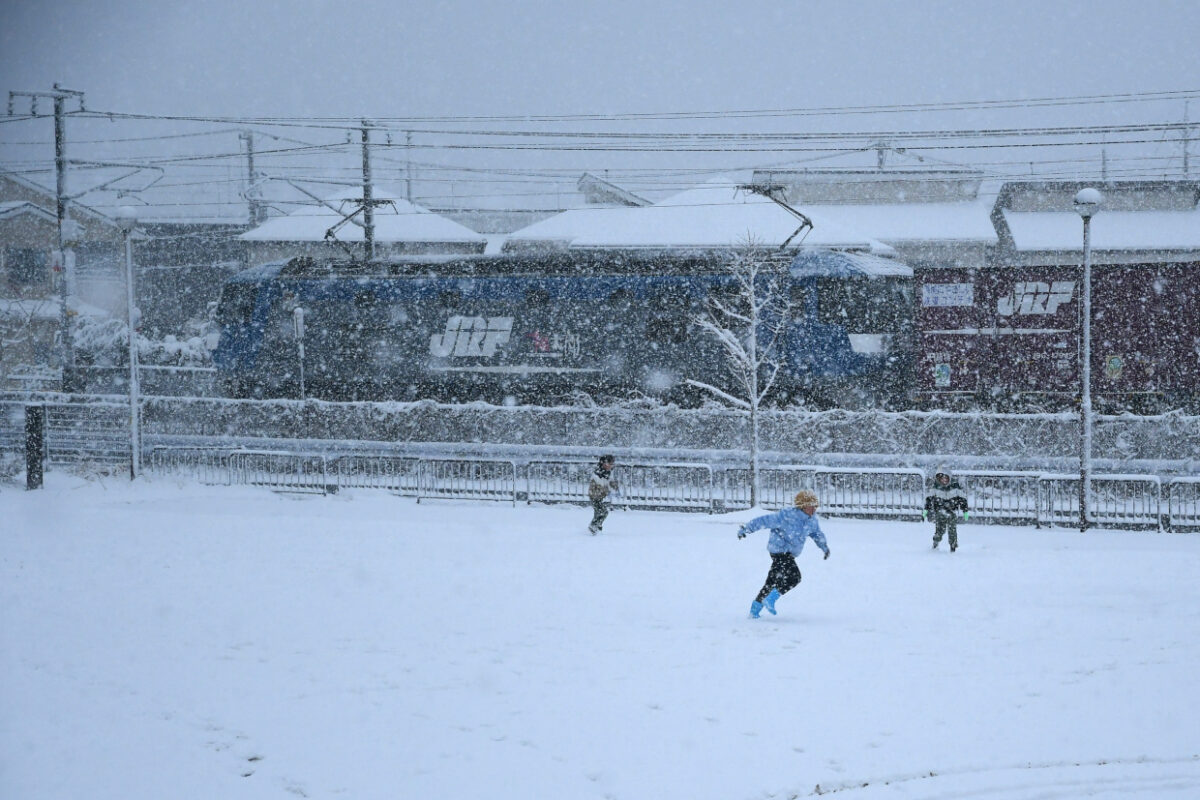 雪の中遊ぶ子どもたちとJR貨物