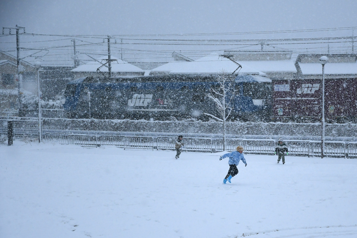 雪の中遊ぶ子どもたちとJR貨物