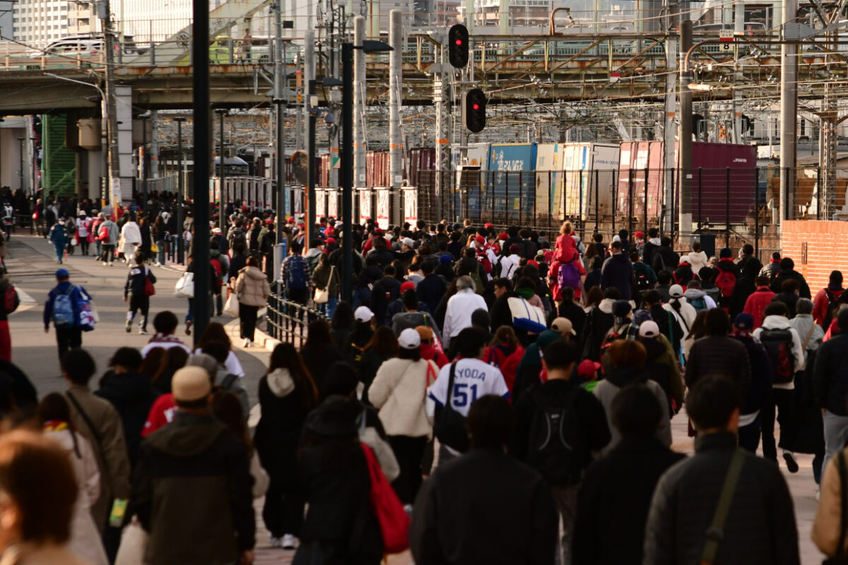 スタジアムから帰途につく観客とJR貨物列車