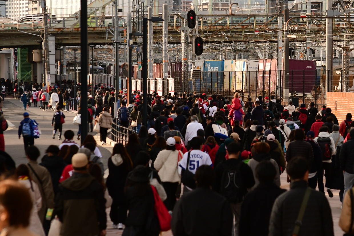 スタジアムから帰途につく観客とJR貨物列車